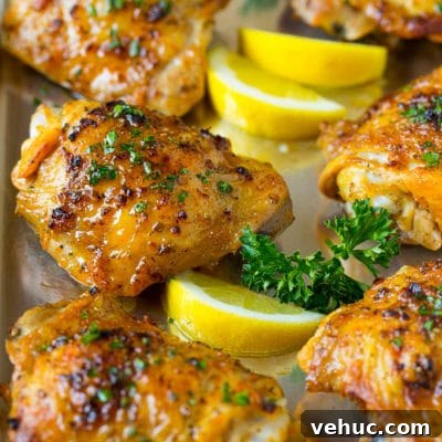 Crispy Oven-Baked Chicken Thighs with Garlic and Herbs 7 A pan of baked chicken thighs garnished with parsley and lemon.
