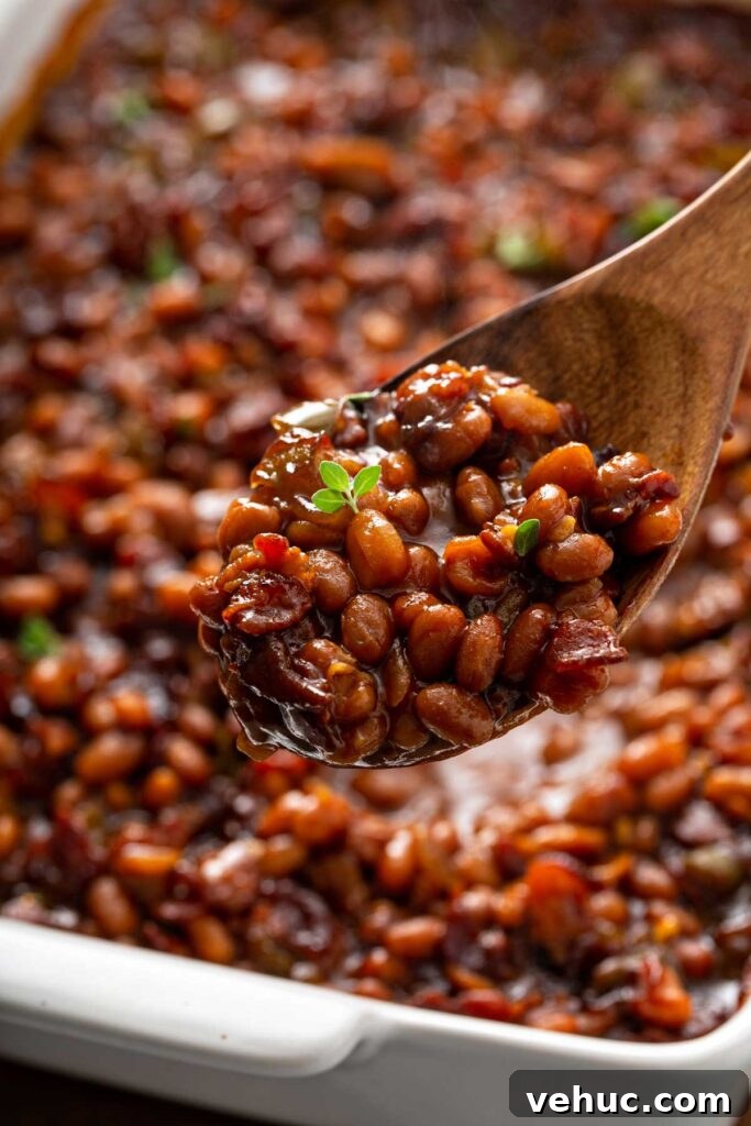 Classic Homemade Baked Beans Recipe for Flavorful Comfort Food 2 Serving baked beans with a wooden spoon from a baking dish