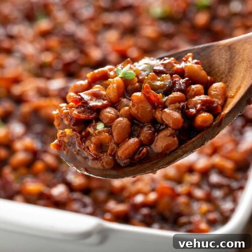 Classic Homemade Baked Beans Recipe for Flavorful Comfort Food 9 Homemade baked beans served with a wooden spoon from a white baking dish