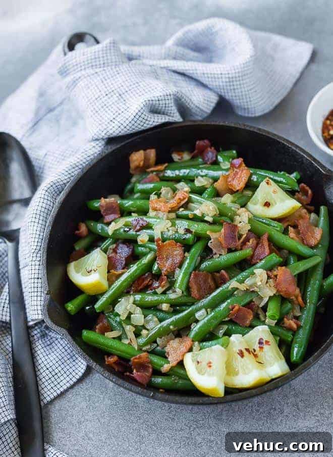 Crispy Bacon Green Beans with Garlic and Caramelized Onions 5 green beans with bacon in a cast iron skillet, garnished with lemon wedges