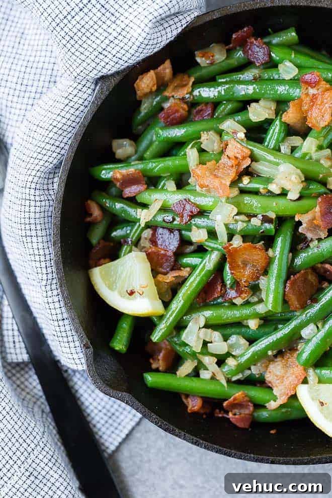 Crispy Bacon Green Beans with Garlic and Caramelized Onions 6 Overhead view of green beans and bacon in a black skillet.