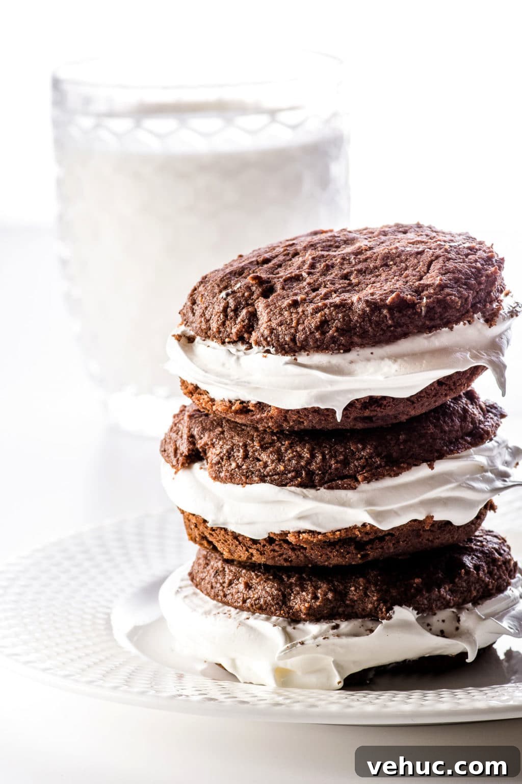 Keto Whoopie Pies with Marshmallow Filling — Low-Carb Gluten-Free 8 Stacked whoopie pies on a white plate in front of a glass of cashew milk