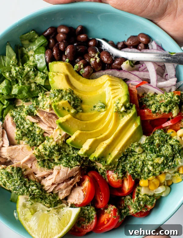 Teriyaki Salmon Bowl Recipe with Rice and Veggies 11 Colorful bowl of flaked tuna with vegetables and an herb dressing drizzled on top.