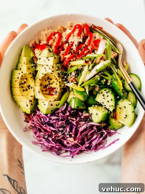 Teriyaki Salmon Bowl Recipe with Rice and Veggies 12 Hands holding up a bowl of canned tuna with various veggies.