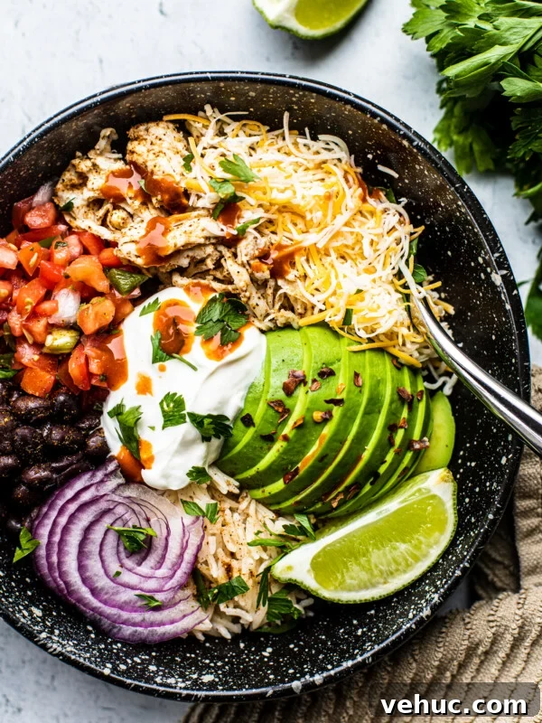 Teriyaki Salmon Bowl Recipe with Rice and Veggies 13 Black bowl filled with rice, pico de gallo, black beans, onions, avocado, and shredded chicken.