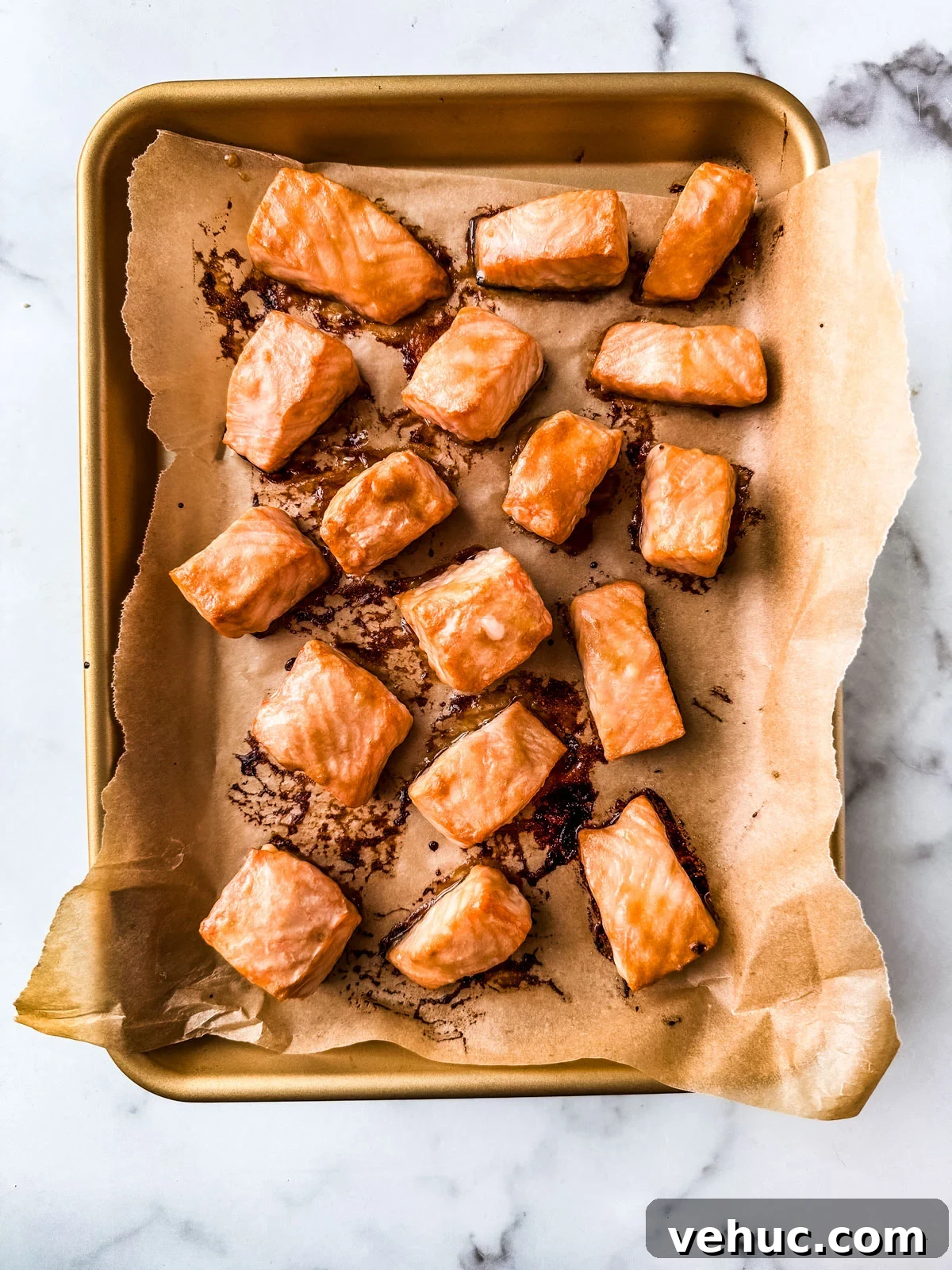 Teriyaki Salmon Bowl Recipe with Rice and Veggies 7 Cooked salmon cubes on a parchment-lined baking sheet.