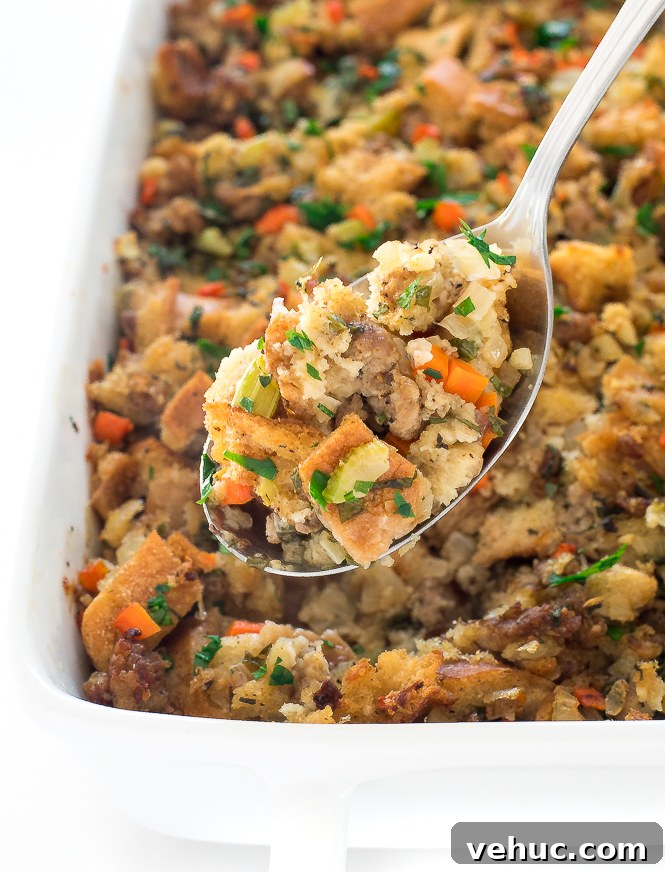 Sausage Stuffing | chefsavvy.com spooning serving of sausage stuffing out of white casserole dish