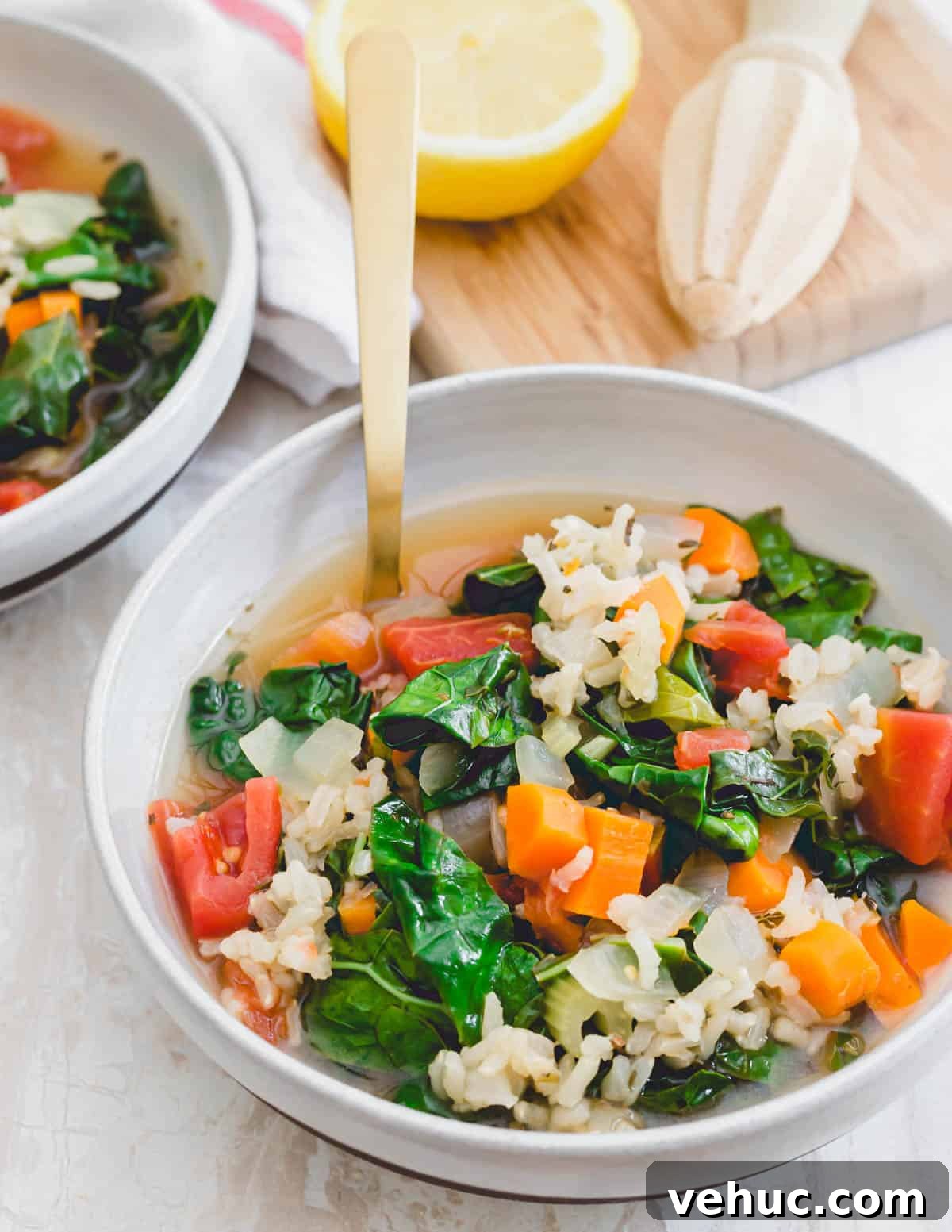 Tuscan kale soup in a bowl with a serving spoon and lemon. Tuscan kale soup in a bowl with a serving spoon and lemon.