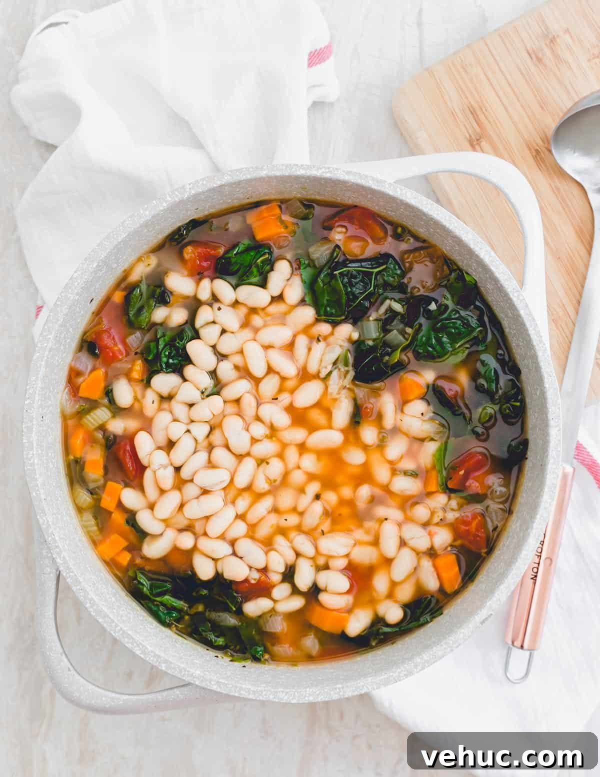 A pot of Tuscan kale soup with added white beans and ladle on the side. A pot of Tuscan kale soup with added white beans and ladle on the side.