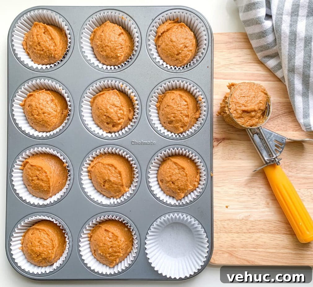 Pumpkin Muffins with Cinnamon Streusel Topping 5 A muffin pan with pumpkin batter in all but one cup. A cookie scoop full of batter is off to the side.