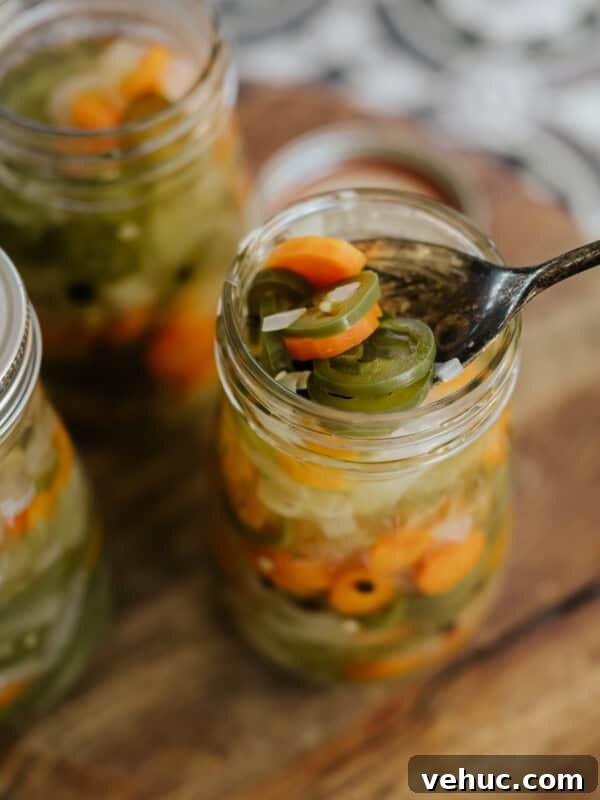 Authentic Cochinita Pibil Tacos Recipe — Yucatan Slow-Roasted Pork 12 multiple mason jars filled with Mexican escabeche on a wooden cutting board with the closest one with a spoon in it fishing out a serving.