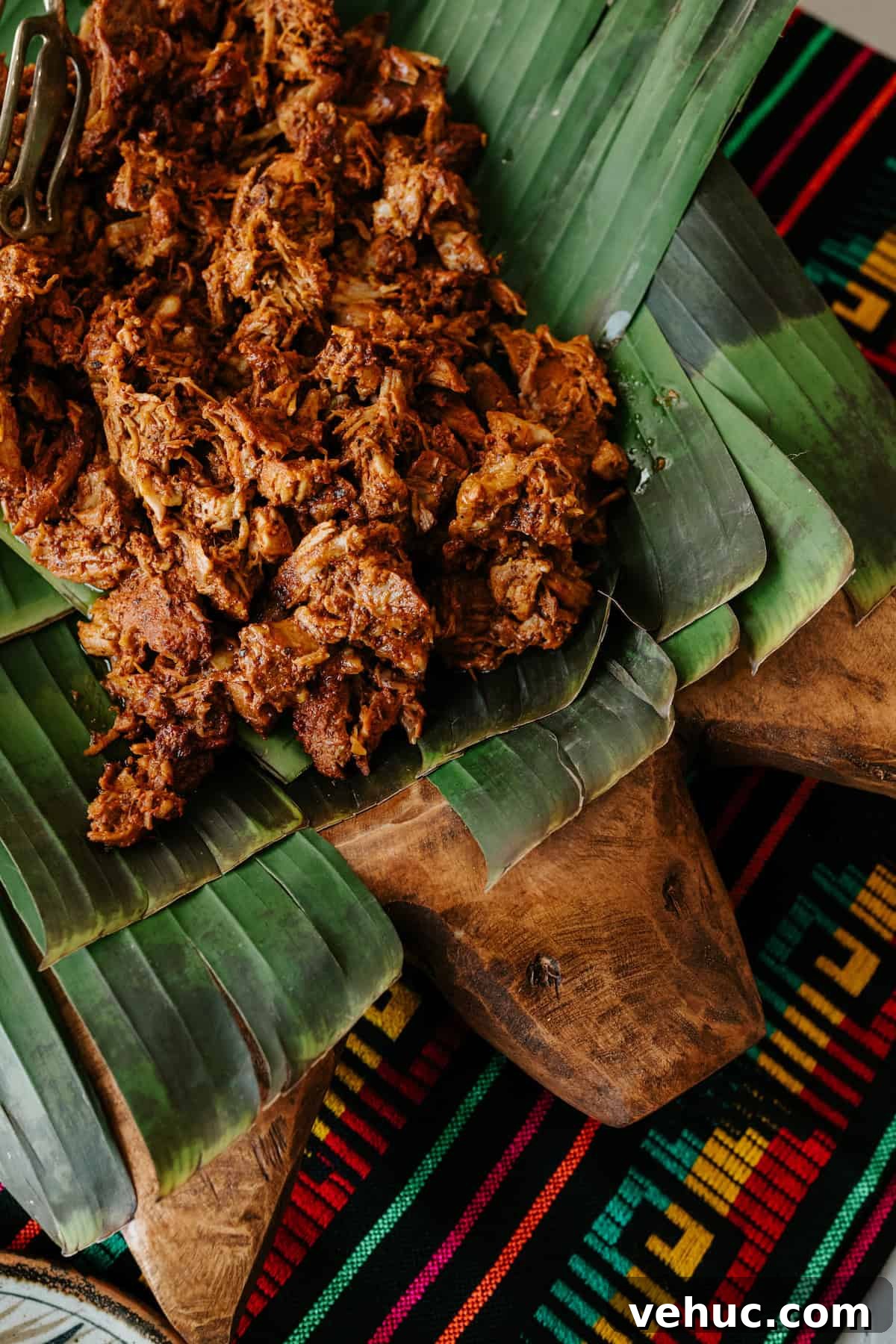 Authentic Cochinita Pibil Tacos Recipe — Yucatan Slow-Roasted Pork 7 Shredded Cochinita Pibil served on banana leaves atop a wooden pig platter, showcasing its deep red-orange color and tender texture.