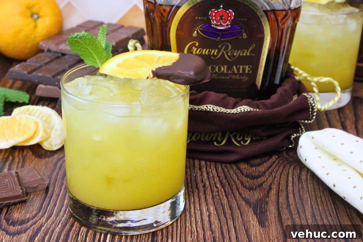 12 Irresistible Chocolate Crown Royal Cocktails to Try Tonight 11 chocolate orange smash drink garnished with mint and chocolate covered orange next to chocolate crown royal bottle