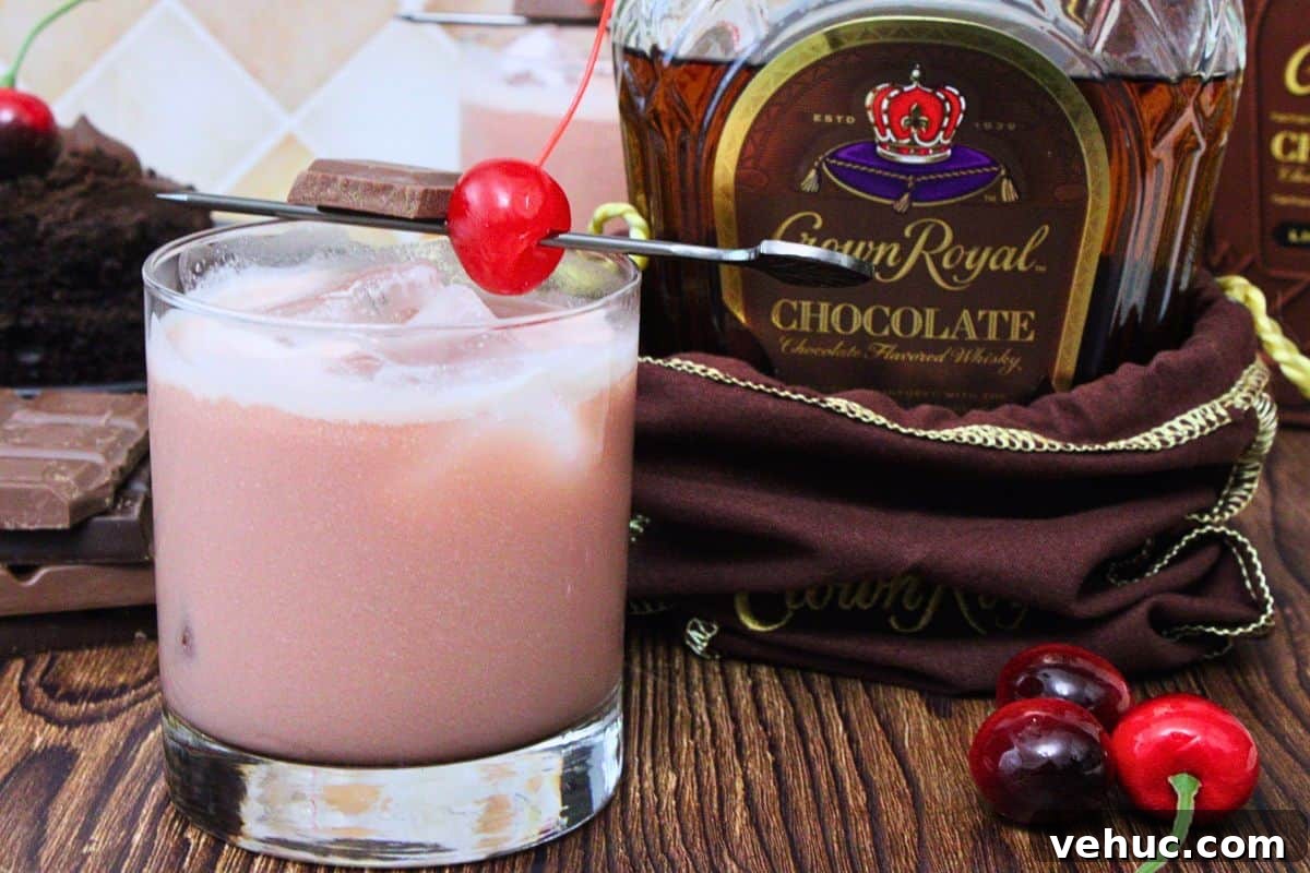 12 Irresistible Chocolate Crown Royal Cocktails to Try Tonight 6 black forest cake cocktail with maraschino cherry next to chocolate crown royal bottle on a wooden table