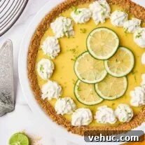 Authentic Florida Key Lime Pie Recipe You’ll Love 8 Florida Key lime pie with graham cracker crust, topped with whipped cream and lime slices in a white pie plate.