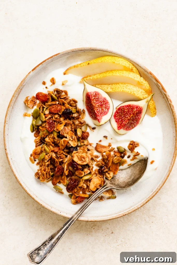 Overhead view of a bowl of yogurt topped with granola, sliced pears, and figs.