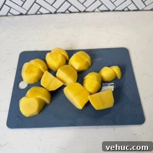 Creamy Garlic Mashed Potatoes Recipe 5 Chopped potatoes on a cutting board.