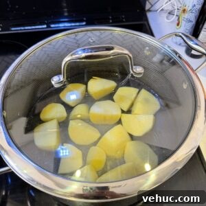 Creamy Garlic Mashed Potatoes Recipe 6 Potatoes boiling in a pot.