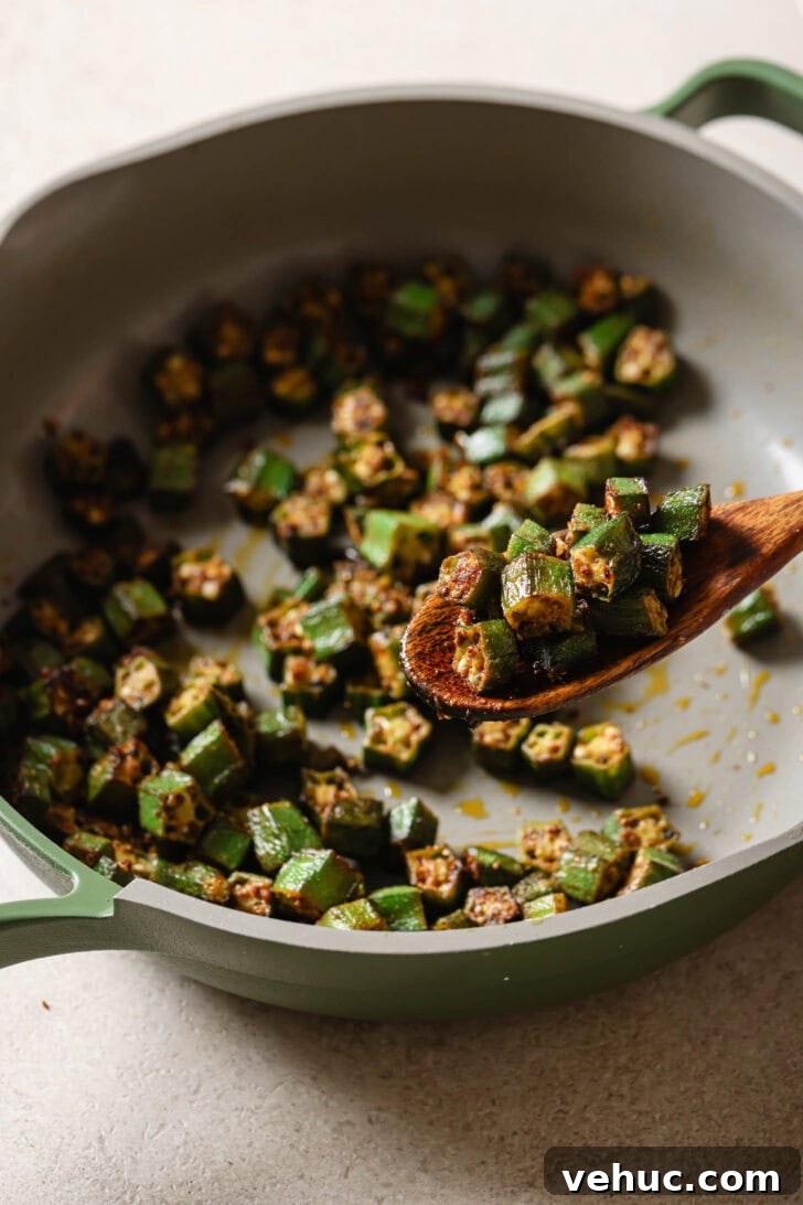 15-Minute Indian-Style Bhindi Fry Recipe for Crispy Okra 13 Holding a spoonful of Bhindi Fry over a skillet.