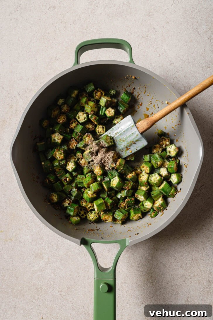 15-Minute Indian-Style Bhindi Fry Recipe for Crispy Okra 10 Coriander powder, fennel seeds and salt added to okra in skillet.