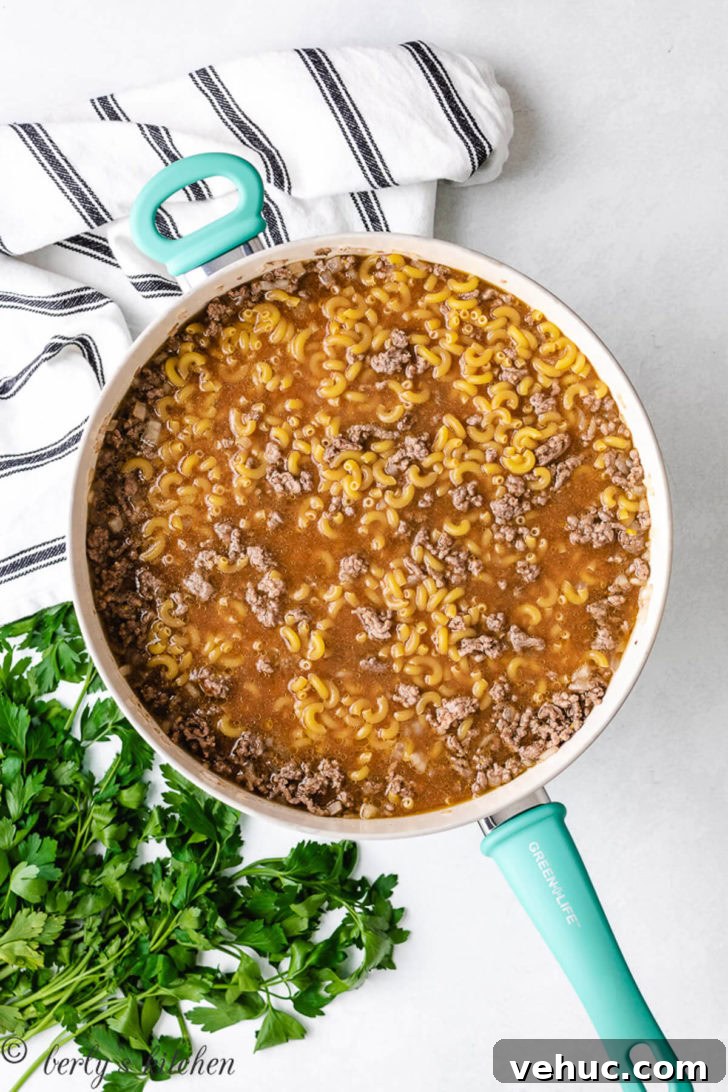 Beef broth and elbow macaroni added to the pan.