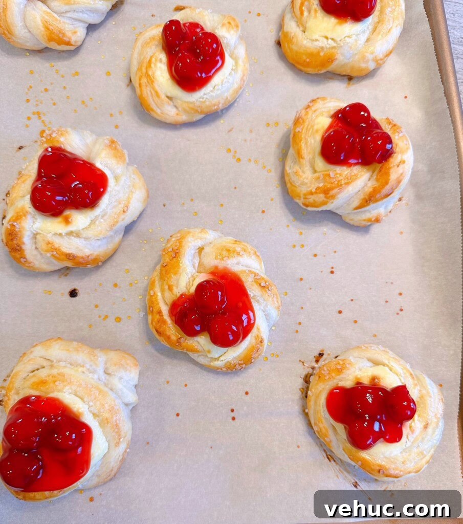 Cherry Cream Cheese Knots: Sweet Stuffed Pastry Bites for Brunch 12 Baked cherry pastries on the baking sheet.