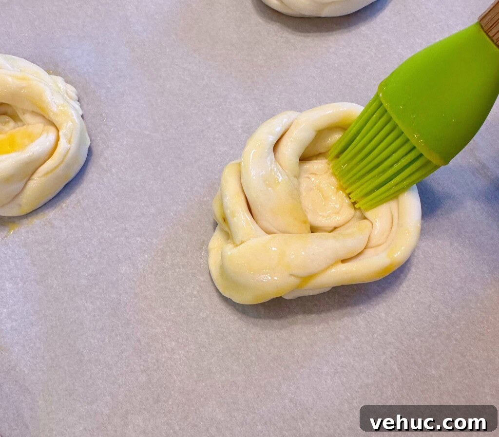 Cherry Cream Cheese Knots: Sweet Stuffed Pastry Bites for Brunch 8 Brushing knots with egg wash.