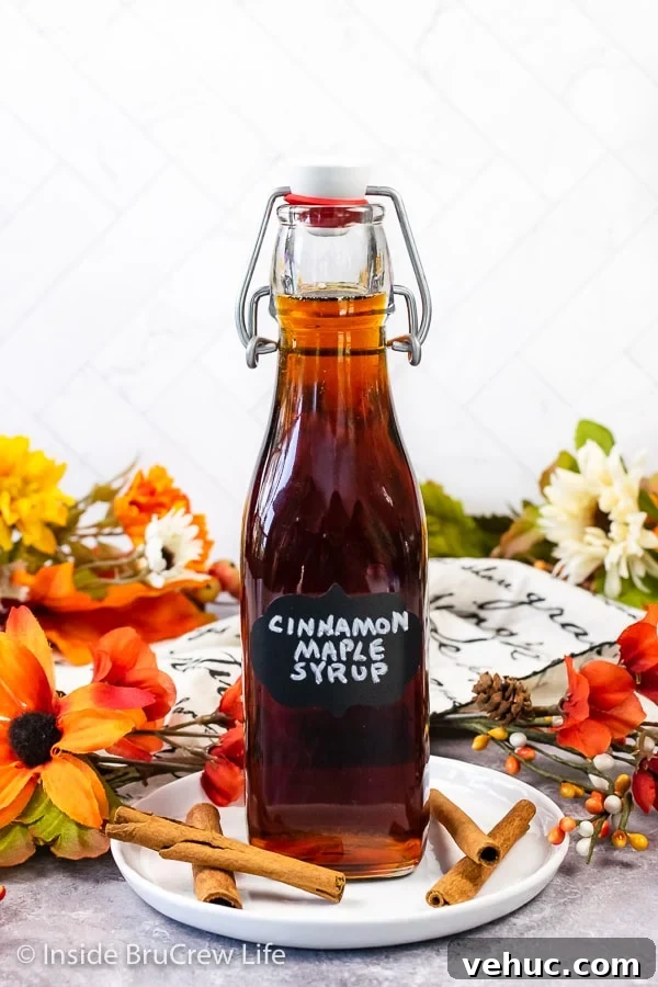 Cinnamon Maple Syrup A clear bottle filled with Cinnamon Maple Syrup with a black label on it.