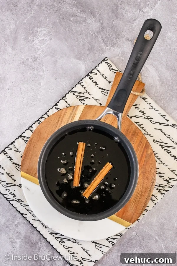 Infusing maple syrup with cinnamon Overhead picture of a saucepan with maple syrup and cinnamon sticks in it.