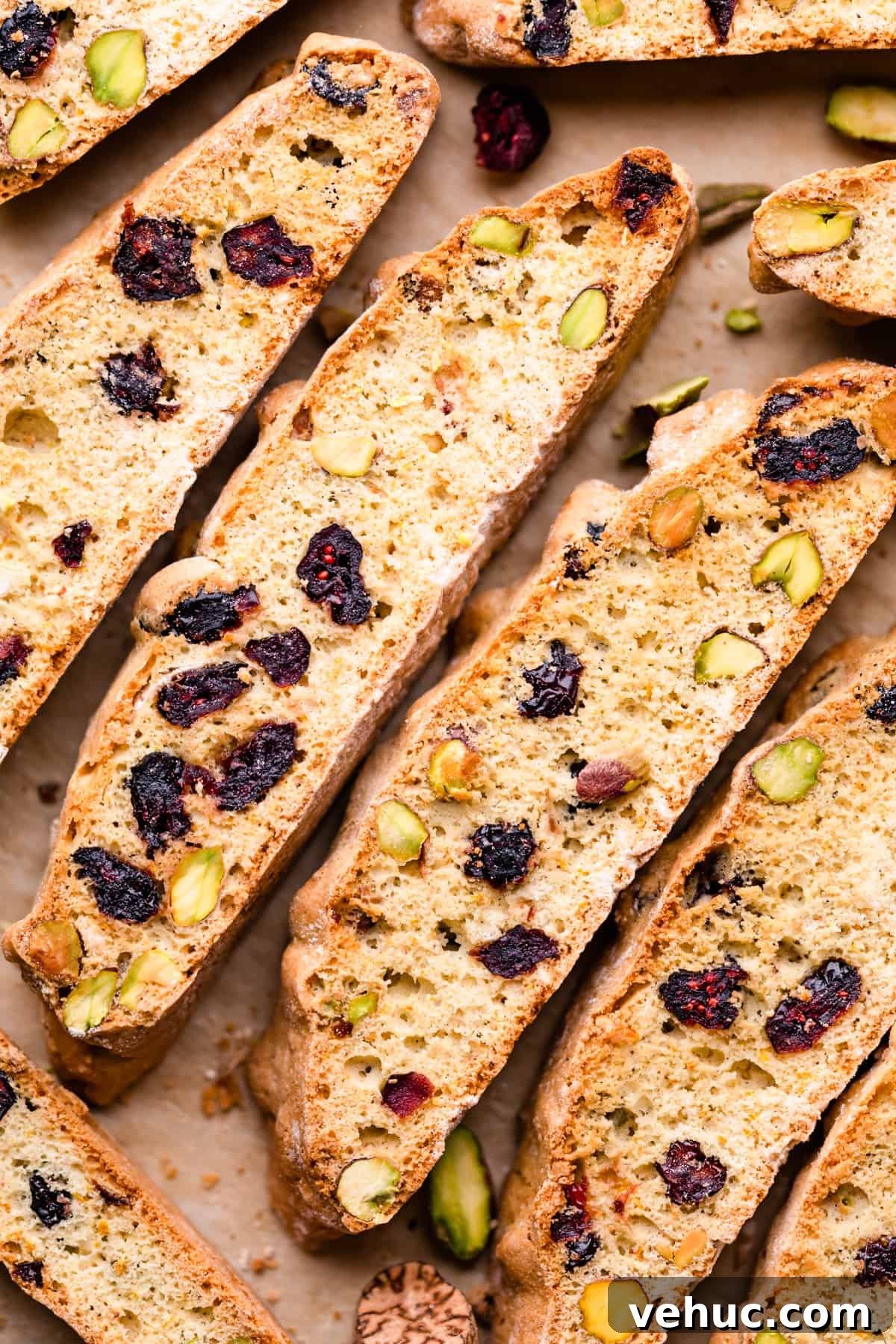 Cranberry Almond Biscotti Recipe for Crunchy Coffee Cookies 2 biscotti slices stuffed with dried cranberries and pistachios arranged next to each other.