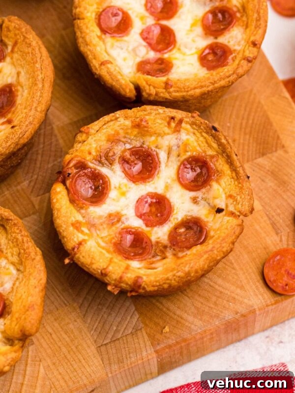 Baked Brie with Honey and Crispy Puff Pastry 7 Golden crusted pizza cupcakes on a wooden cutting board.