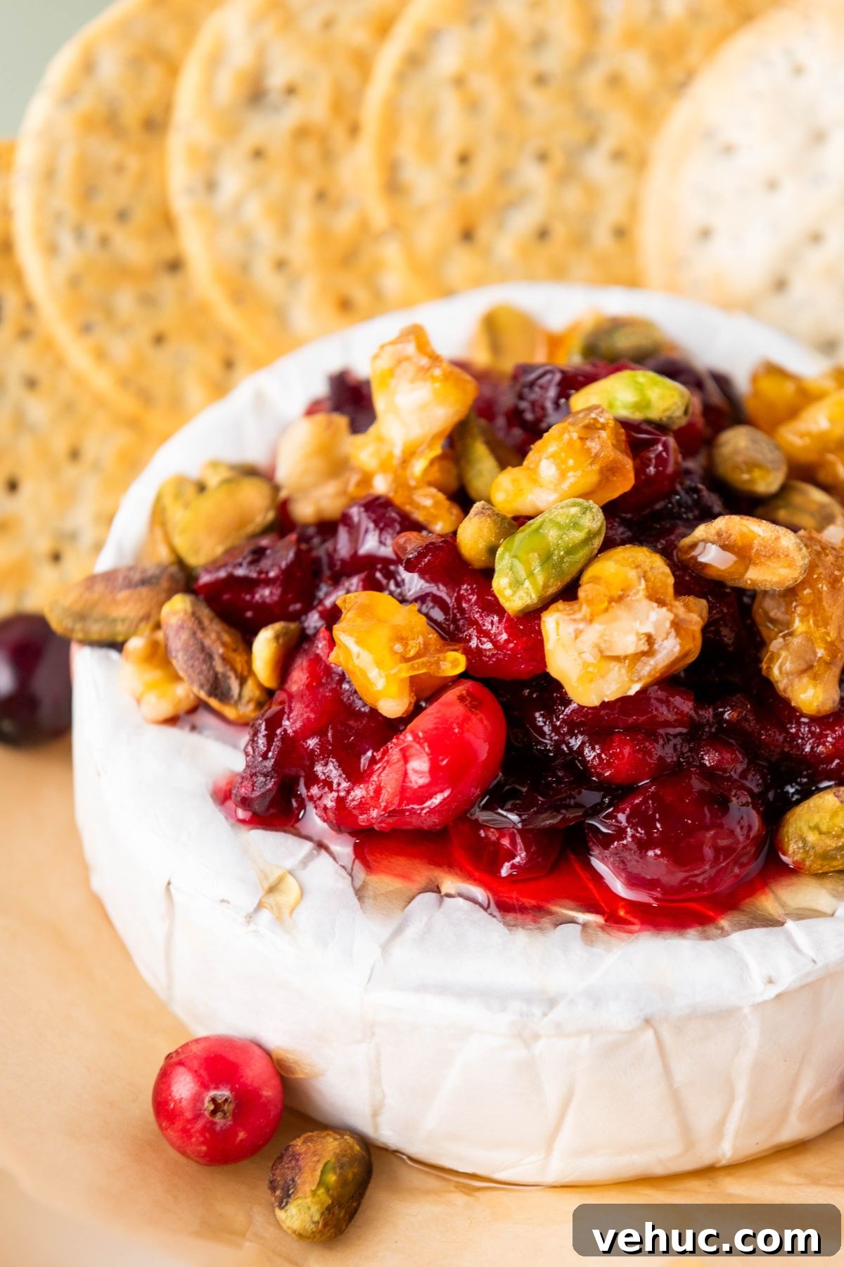 Baked Brie with Honey and Crispy Puff Pastry 5 A round block of brie cheese, topped with nuts and cranberries, surrounded by crackers.