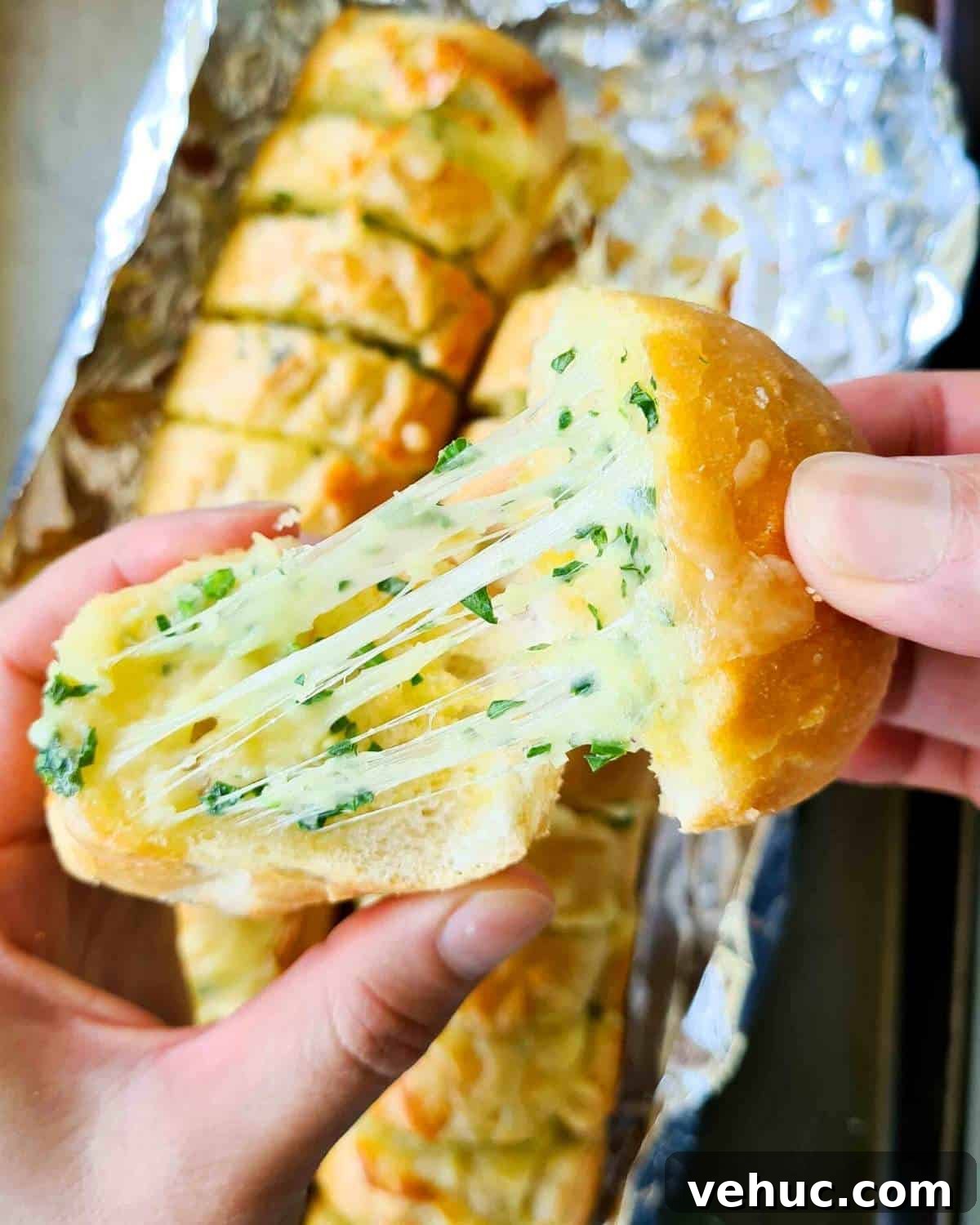 Irresistible Cheesy Garlic Bread Recipe for Perfect Crispy Loaves 7 Two slices of freshly baked cheese garlic bread being pulled apart, showing lots of cheese strech