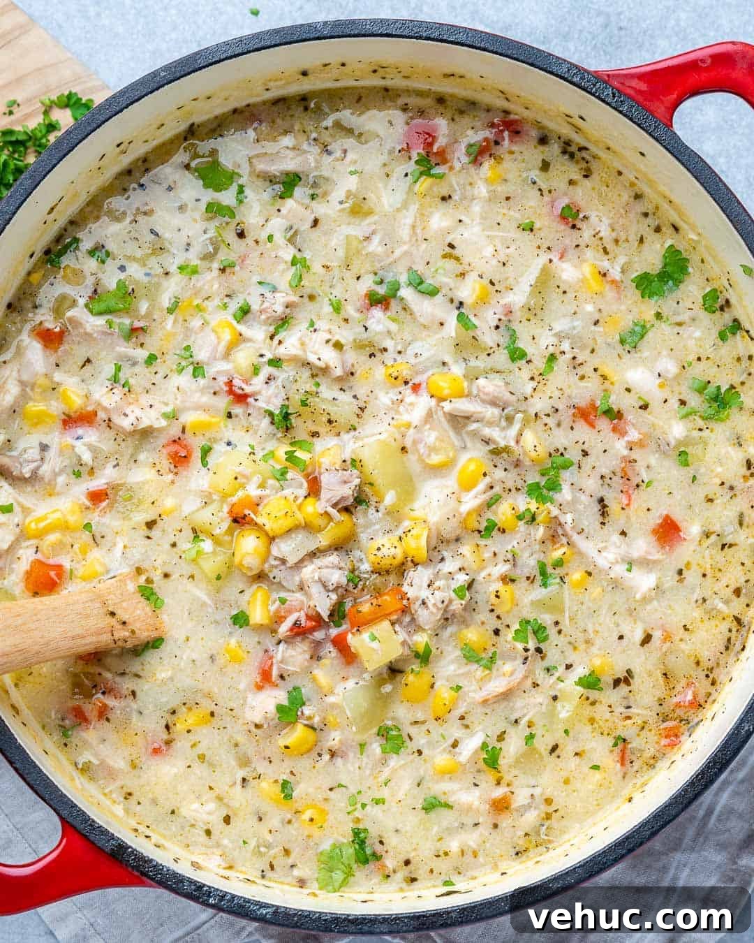 Creamy Chicken and Corn Chowder Recipe for Comforting Meals 7 Red pot of chicken Corn Chowder with a wooden spoon inside.