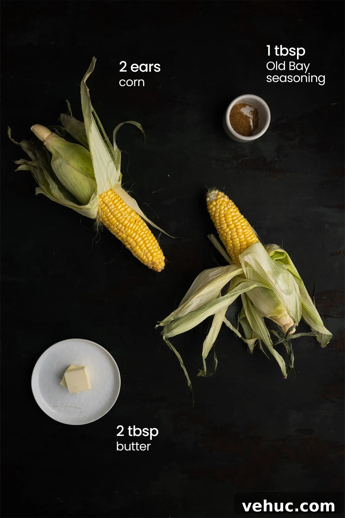 Grilled Corn on the Cob with Zesty Old Bay Seasoning 3 Overhead view of all the ingredients for grilled corn on the cob with Old Bay seasoning - 2 ears of corn, Old Bay seasoning, and butter.
