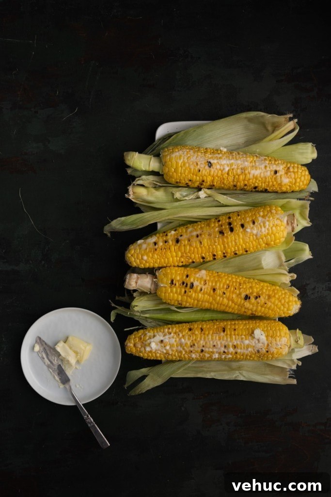 Grilled Corn on the Cob with Zesty Old Bay Seasoning 4 Adding softened butter to grilled corn.
