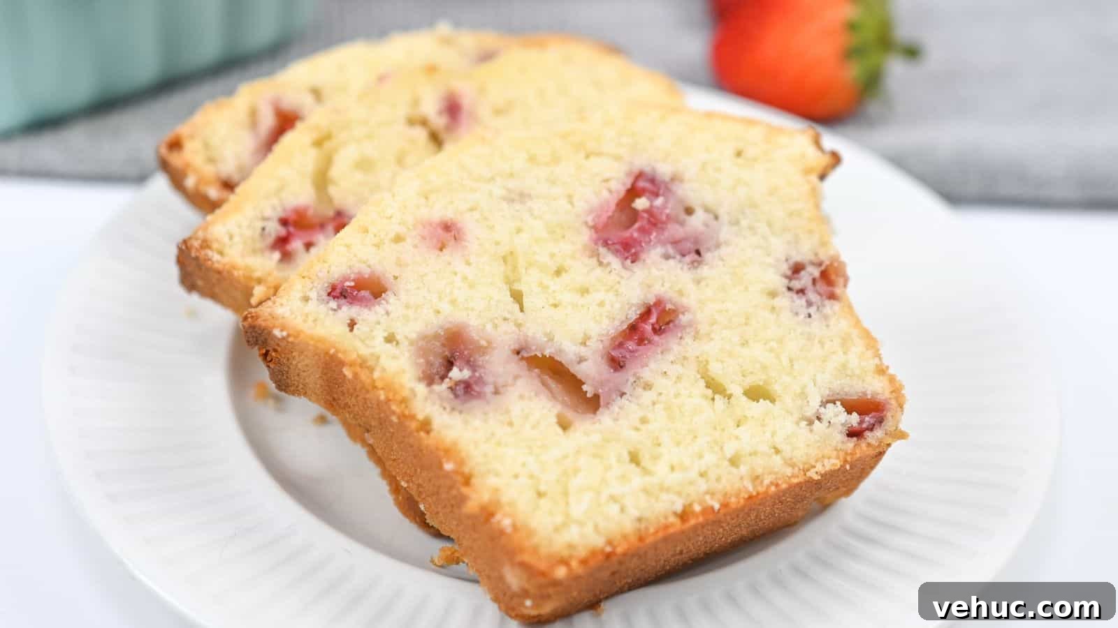 Three slices of strawberry pound cake on a white plate, with visible pieces of strawberry and a slight golden crust.
