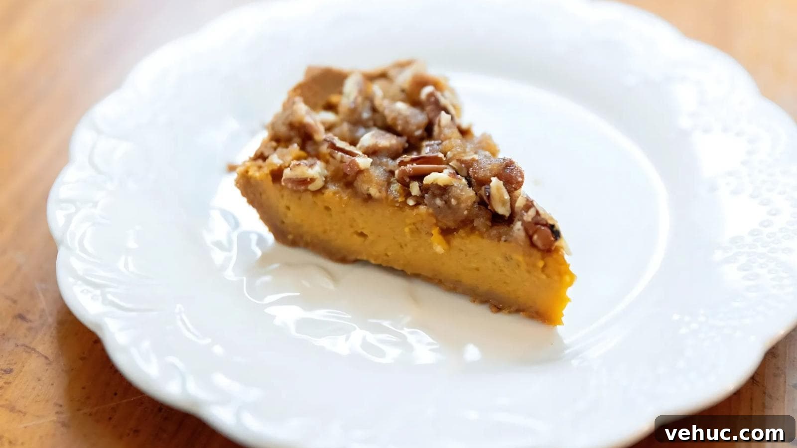 A slice of pumpkin pie topped with pecans on a white plate.