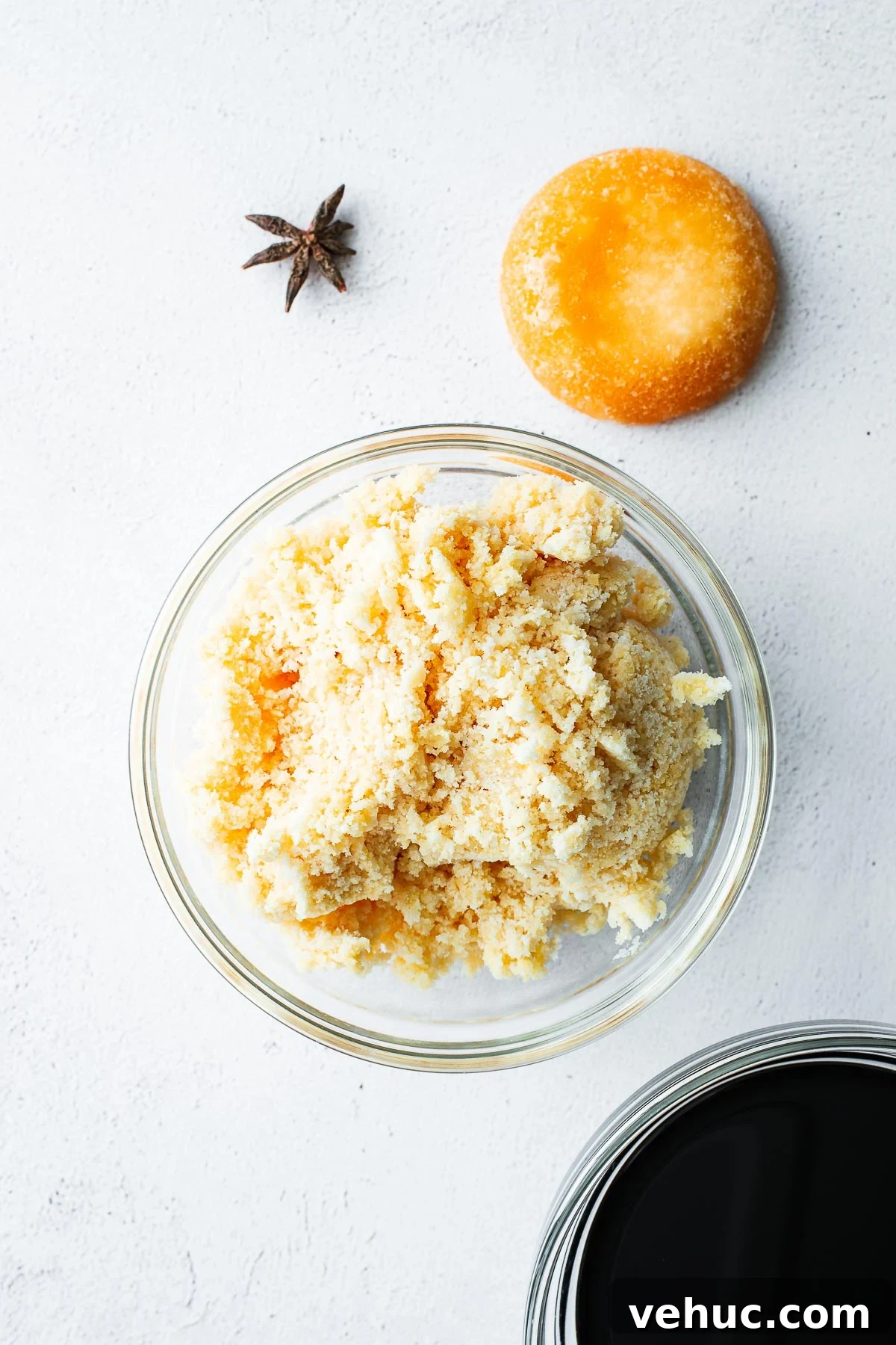 Kecap Manis Substitute: How to Make Sweet Soy Sauce at Home 3 Ingredients for homemade sweet soy sauce (kecap manis) on a light concrete background, including a brick of palm sugar, a bowl of grated palm sugar, a star anise pod and a bowl of all-purpose soy sauce.