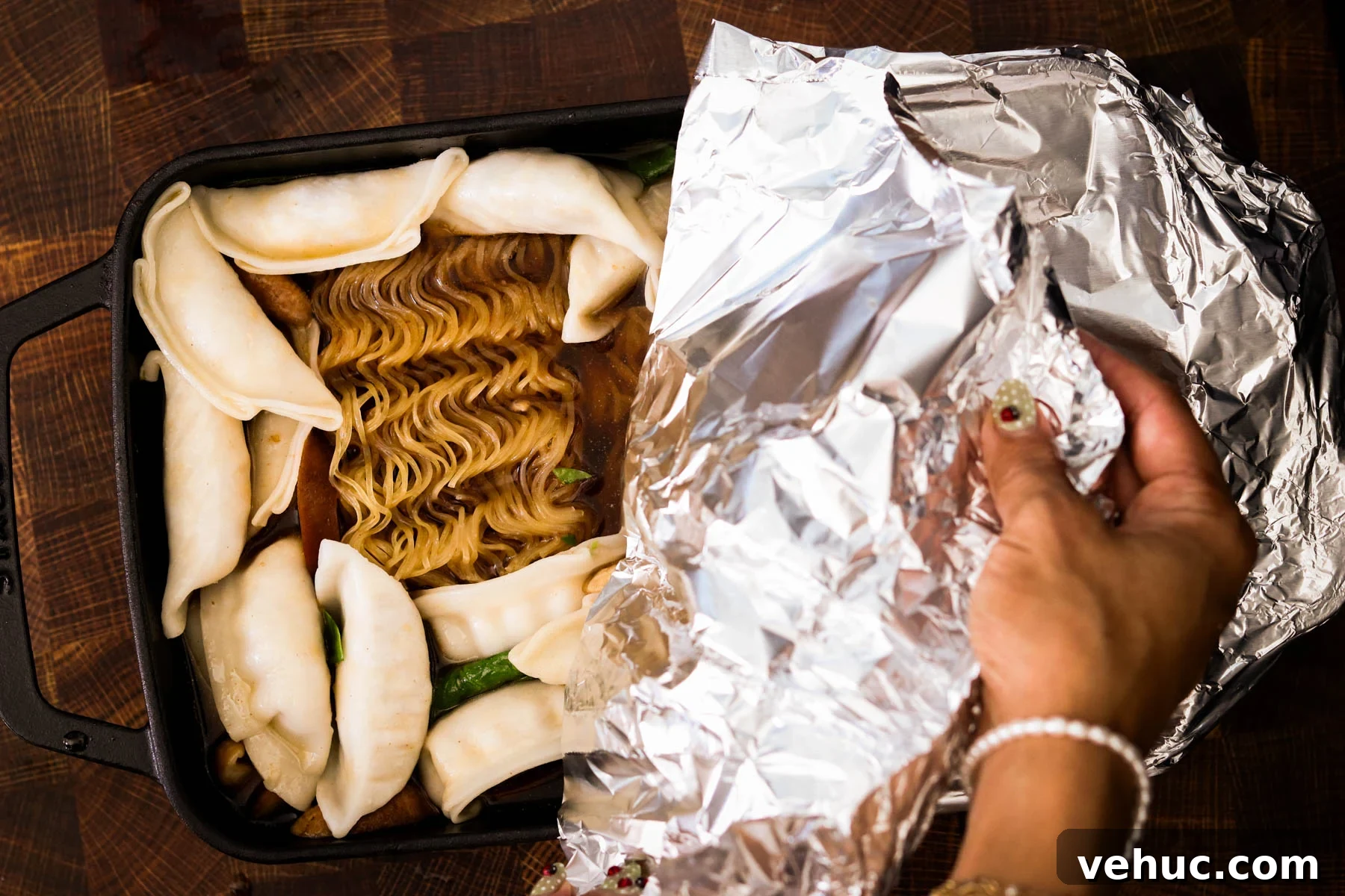 Crispy Baked Dumplings with Ramen: One-Pan Weeknight Dinner 7 Foil being put on baking dish of baked dumplings and ramen.