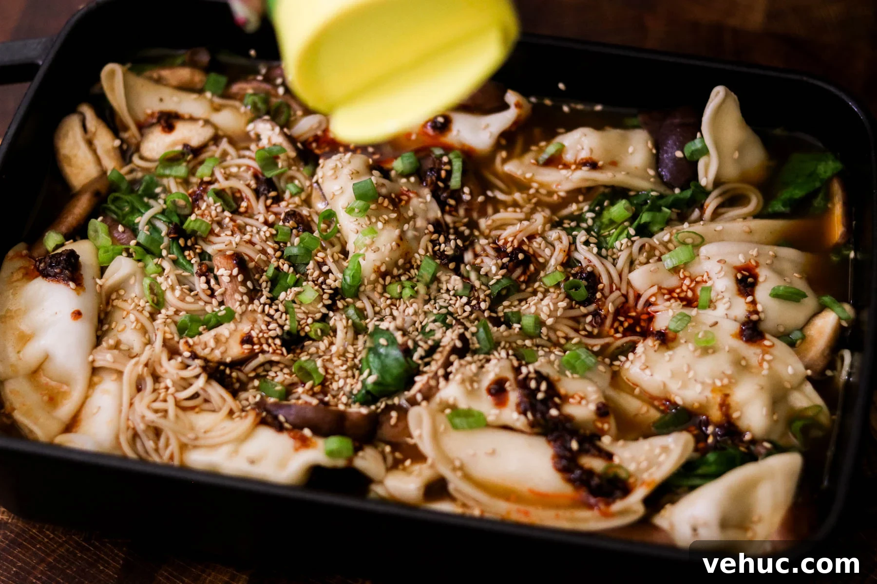Crispy Baked Dumplings with Ramen: One-Pan Weeknight Dinner 9 Finished baked dumplings and ramen garnished with green onions, sesame seeds, and chili oil in a baking dish.