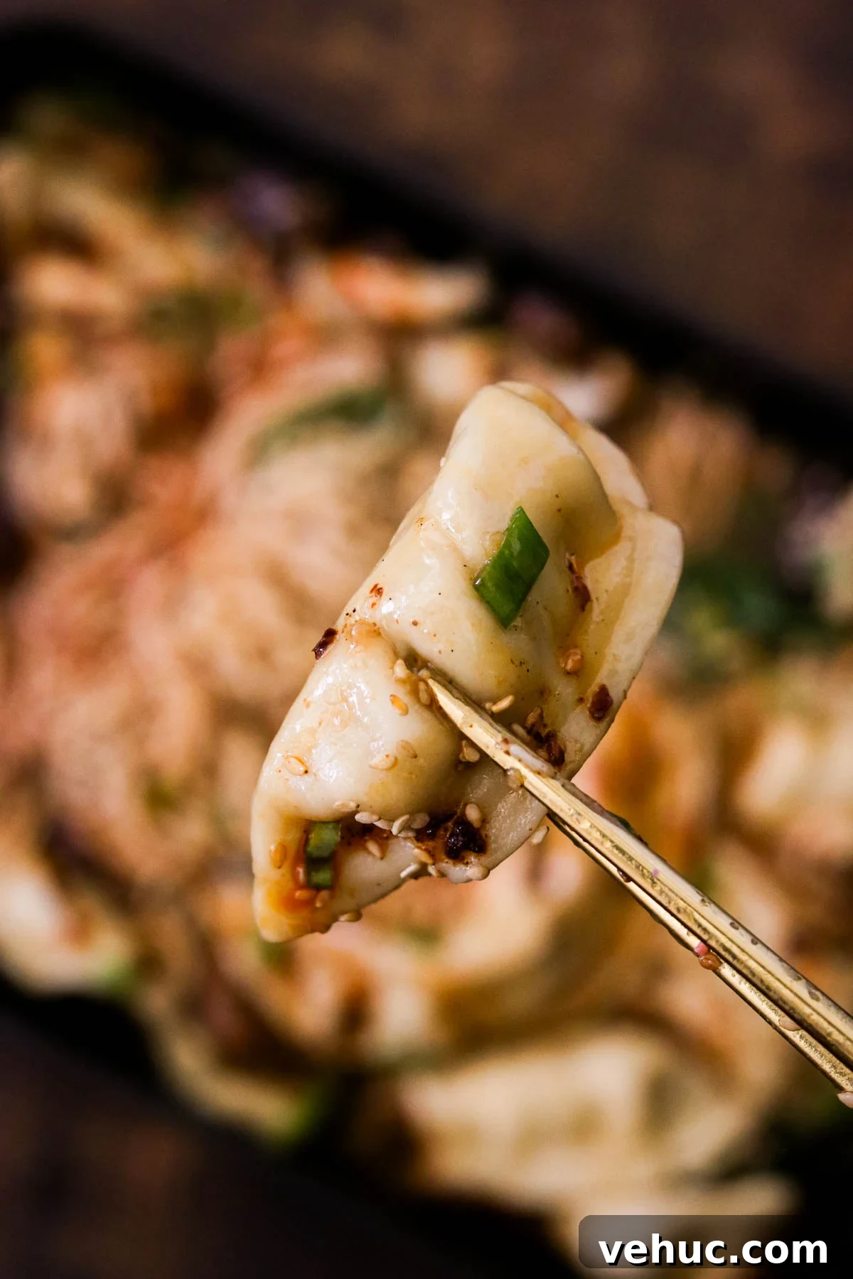 Crispy Baked Dumplings with Ramen: One-Pan Weeknight Dinner 10 Close-up of a baked dumpling being help between two chopsticks.