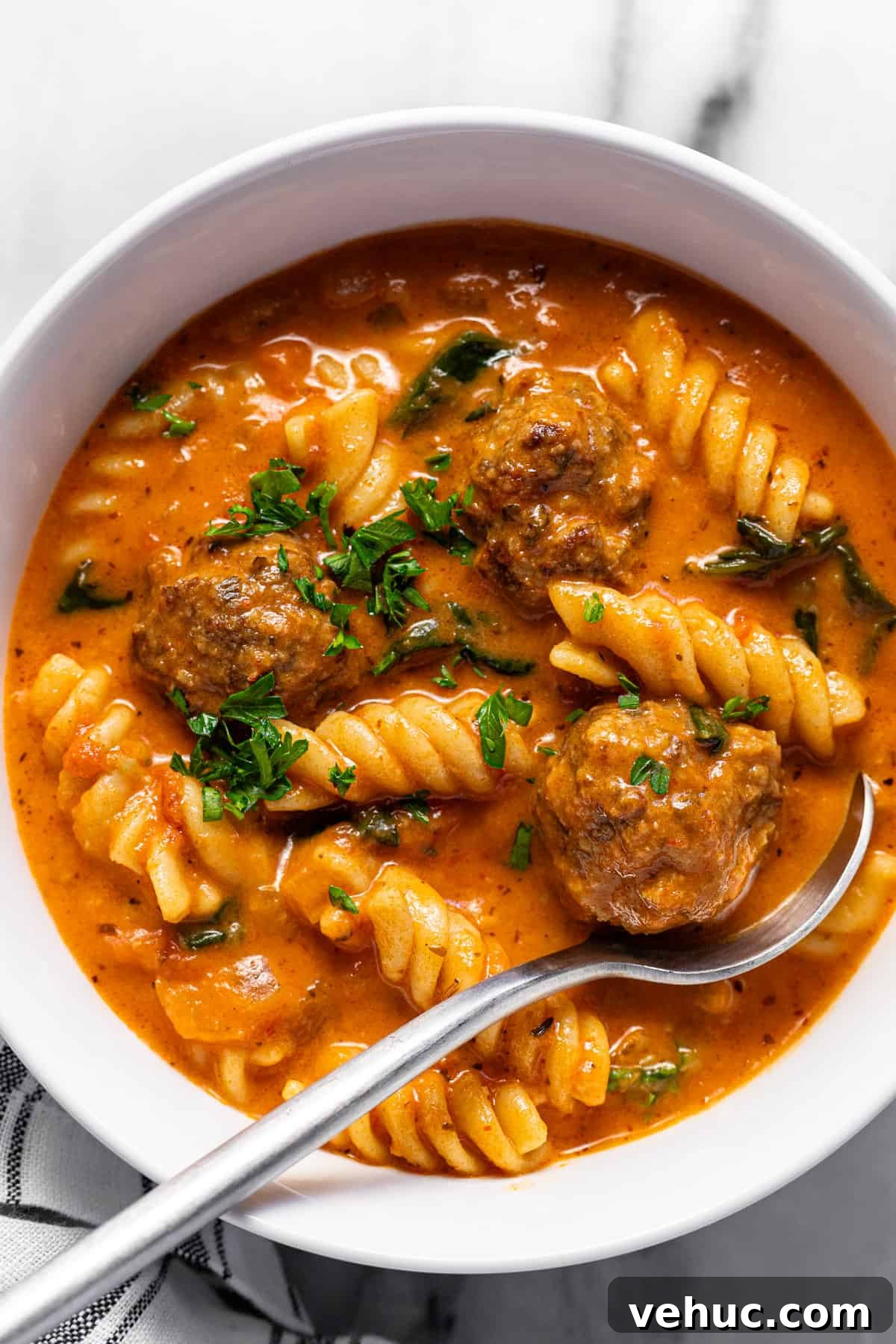 Creamy Italian Meatball Soup: Cozy Weeknight Recipe 2 White bowl filled with creamy homemade Italian meatball soup garnished with parsley.