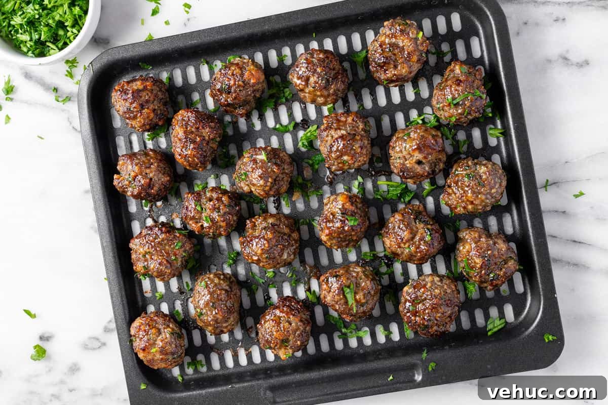 Creamy Italian Meatball Soup: Cozy Weeknight Recipe 4 Black air fryer tray filled with homemade Italian meatballs garnished with parsley.