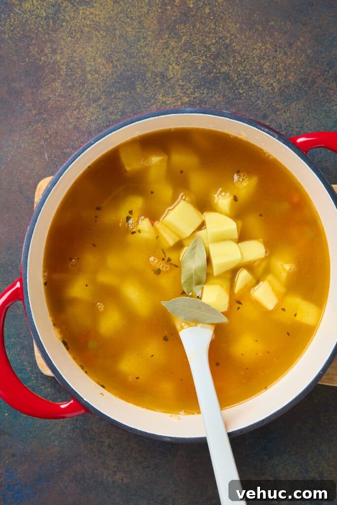 Roasted Poblano and Corn Chowder with Smoky Creaminess 7 A pot of brothy soup with potatoes and bay leaves