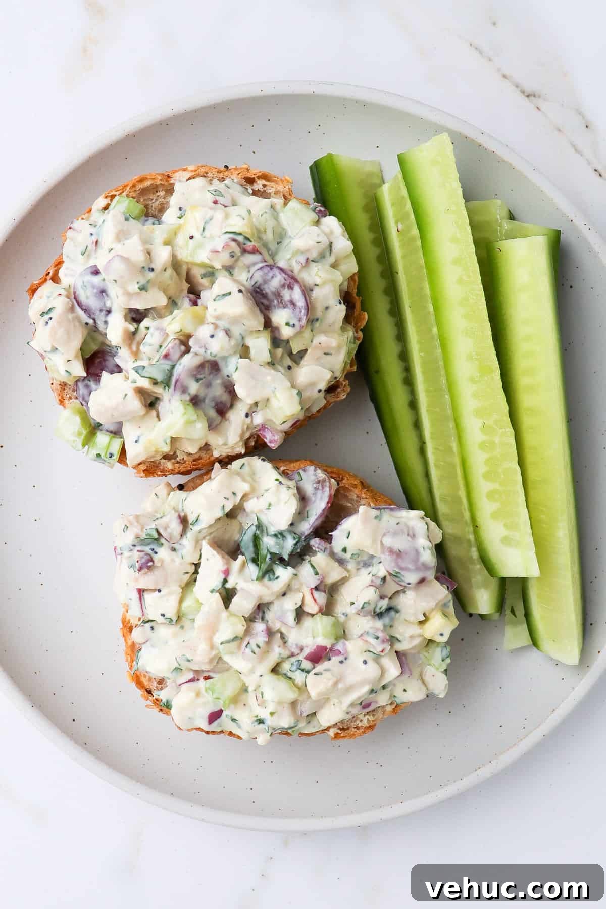 Chicken salad served on bread with cucumber sticks.