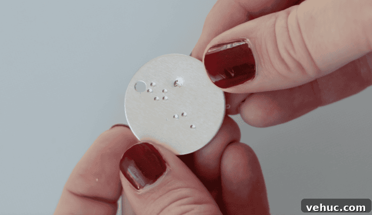 How to Make Stamped Constellation Necklaces (Video) 8 hand holding stamped metal