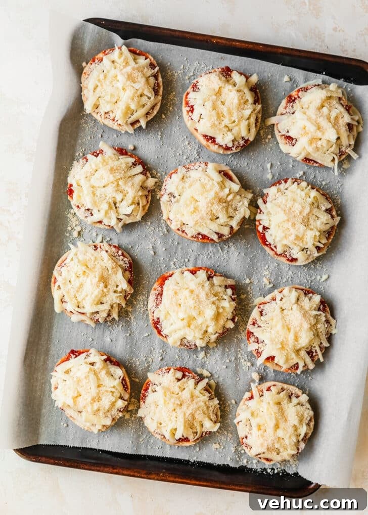 Homemade Pizza Bagel Bites Recipe: Quick Oven & Air Fryer Guide 5 A sheet pan of mini bagels topped with cheese on a tan counter.