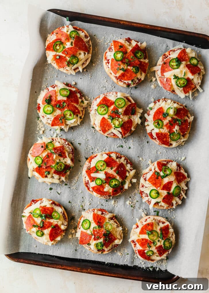 Homemade Pizza Bagel Bites Recipe: Quick Oven & Air Fryer Guide 6 Raw homemade pizza bagel bites with pepperoni and serrano peppers on a sheet pan.