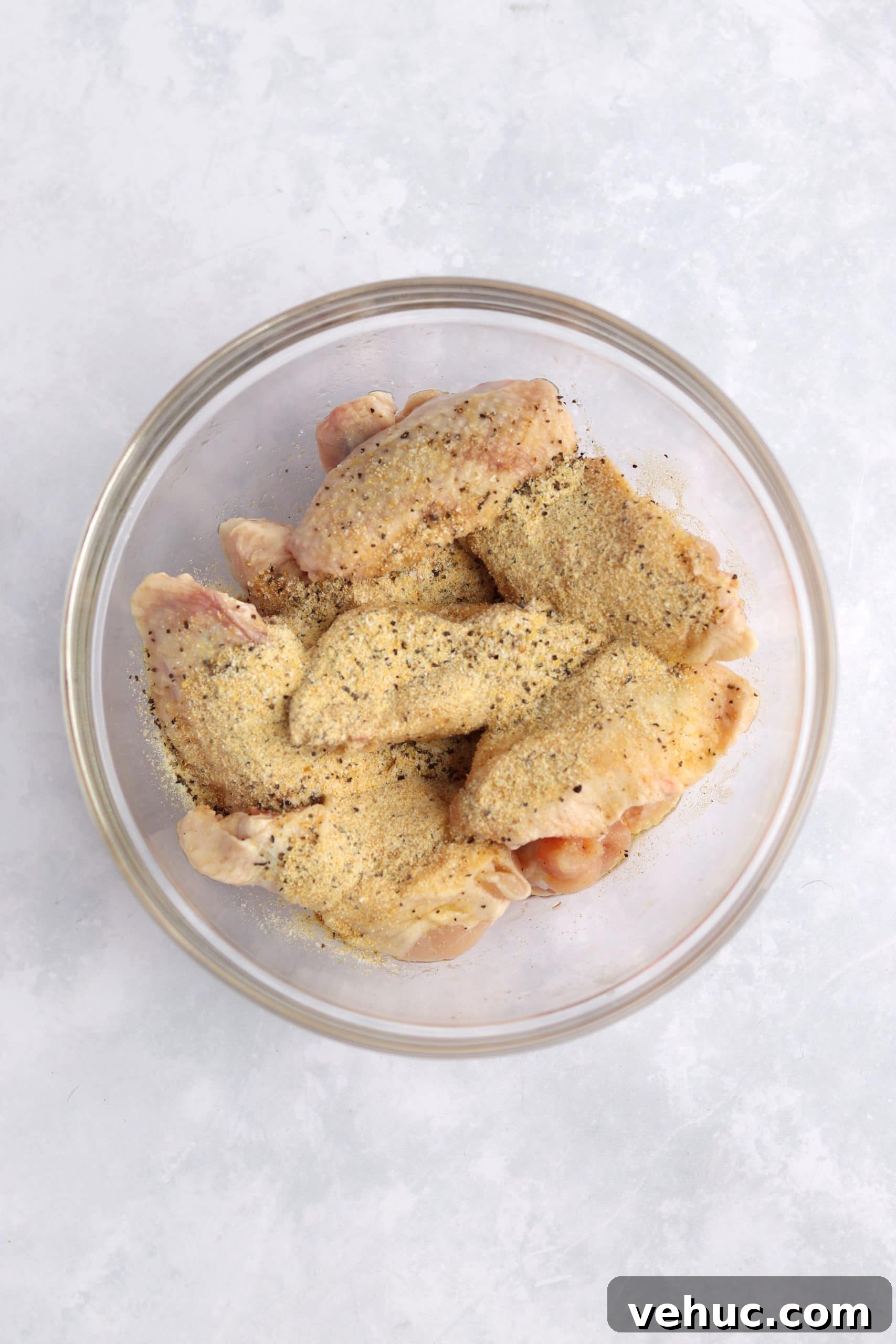 Crispy Air Fryer Chicken Wings Recipe for Perfectly Golden Wings 3 Bowl of raw chicken wings with spices - lemon pepper, garlic powder, and salt